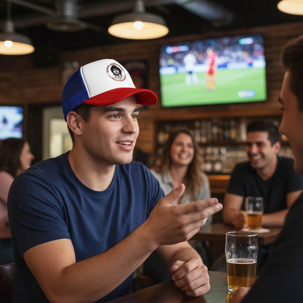 Globalfanz Maradona La Pelota No Se Mancha trucker cap with white front panel, red brim, and blue mesh back. Features a graphic of Maradona.